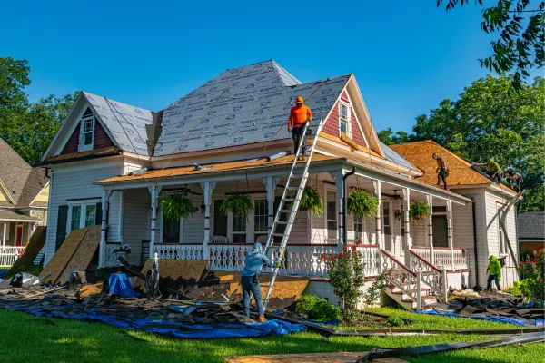 Roofers using ladder to get onto roof of traditional Carolina style home
